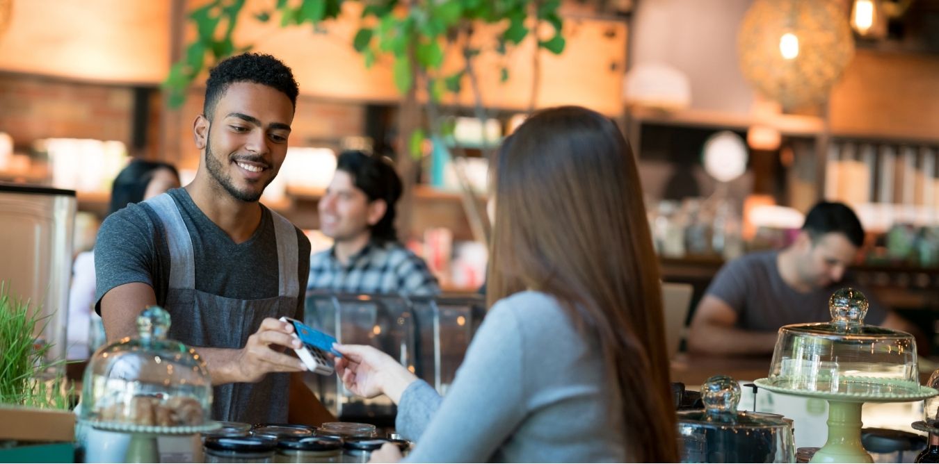 Un serveuse encaisse une cliente avec le paiement sans contact par carte bancaire