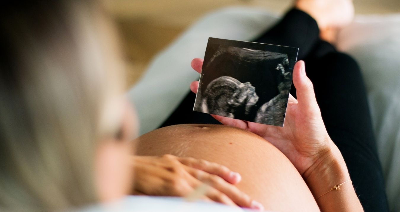 une femme enceinte auto-entrepreneur regarde l'échographie de son enfant pendant son congé maternité